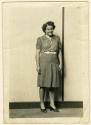 Standing woman in polka-dot dress, striped background