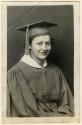 Seated young woman in mortarboard and graduation gown