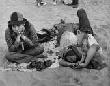 Girl sitting next to couple kissing on beach