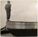 Boy standing on bow of boat seen from behind