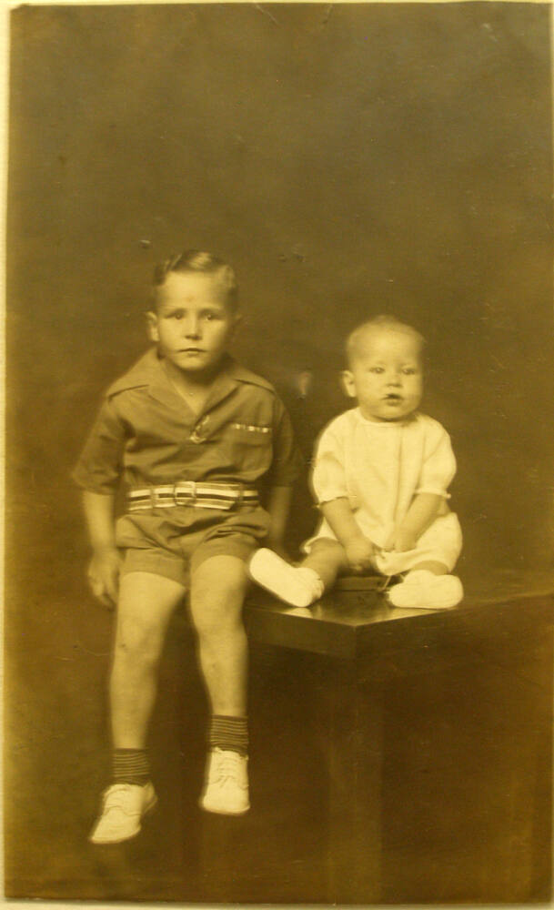 Boy and infant seated on table