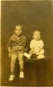 Boy and infant seated on table