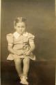 Girl in dress with wide lapels, seated on table