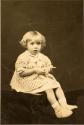 Little girl in knit sweater seated on table